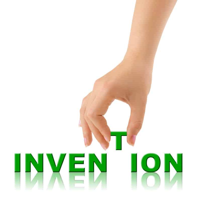 Invention word with the letter T being placed by a hand.